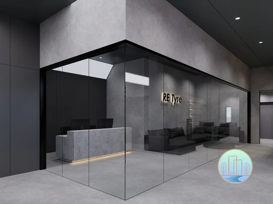 Modern, minimalist office reception area featuring concrete walls, glass partitions, a stone reception desk, and illuminated logo signage.